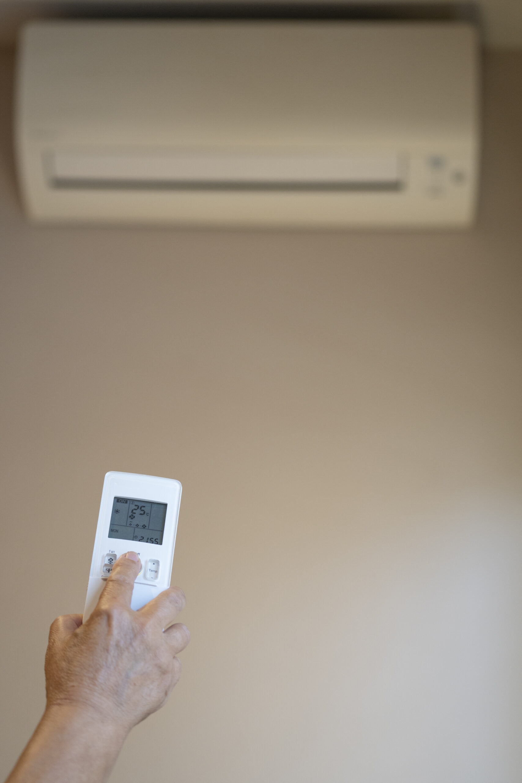 Close-up of old Woman hand operating Air Conditioner With Remote Control. copy space